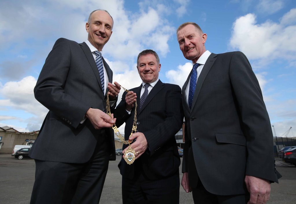 The Institute of Directors Northern Ireland (IoD NI) has appointed Gordon Milligan as its new Chairman. He is pictured, centre, accepting the chain of office from outgoing Chairman Ian Sheppard, at the premises of construction firm Henry Brothers, alongside David Henry, Managing Director of Henry Brothers. Mr Milligan, who is Deputy Chief Executive of Translink, said he planned to put member engagement at the top of his agenda.