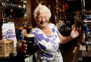 Dame Mary Peters CH, DBE celebrates ticking ‘pulling a pint’ off her bucket list in the Dark Horse, Belfast to launch the final push towards ‘Mary’s Race to a Million.’